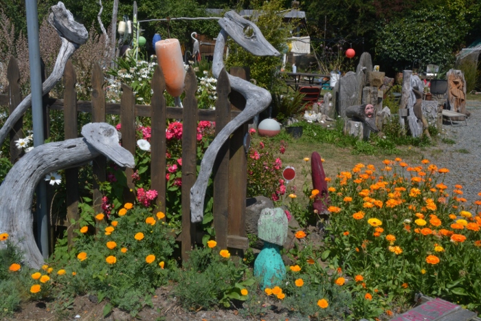 A residential garden filled with flowers and nautical artistic junk